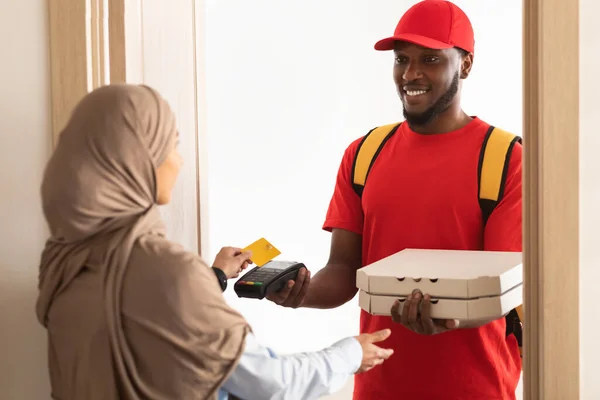 Glimlachende bezorger met POS machine, vrouw die betaalt met een kaart — Stockfoto