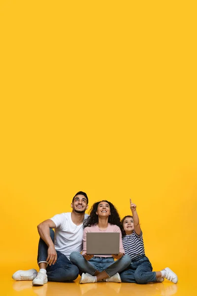 Joyful Arab Family Of Three With Laptop Pointing Up At Copy Space — Stock Photo, Image