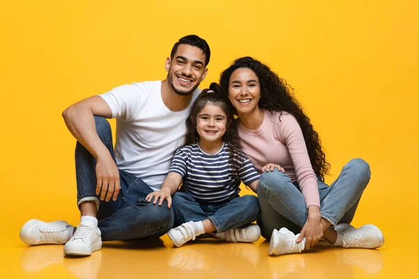 Retrato de pais árabes sorridentes e pequena filha posando sobre fundo amarelo — Fotografia de Stock