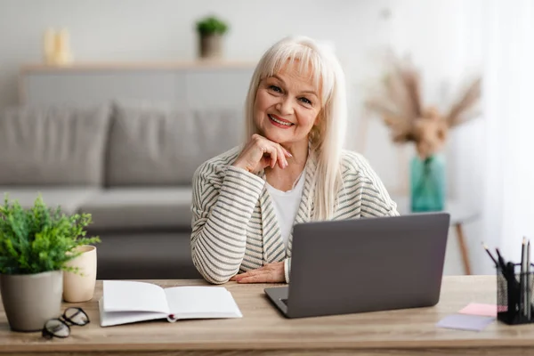 Volwassen vrouw zitten aan bureau met computer poseren op camera — Stockfoto