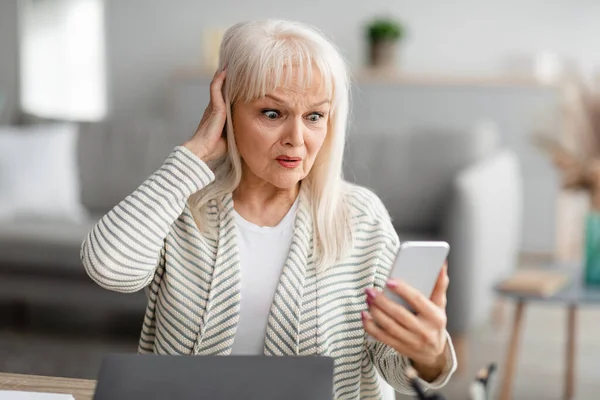 Mujer mayor conmocionada usando su teléfono móvil — Foto de Stock