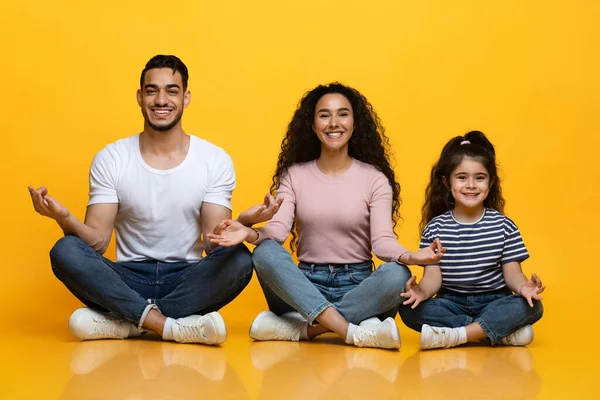 Alegres pais e filha do Oriente Médio sentados em posição de lótus em fundo amarelo — Fotografia de Stock
