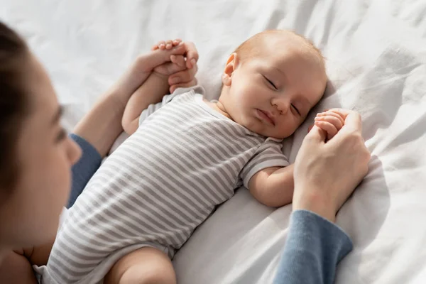 Cuidado de la madre. Amar a mamá sosteniendo las manos de su adorable bebé recién nacido dormido —  Fotos de Stock