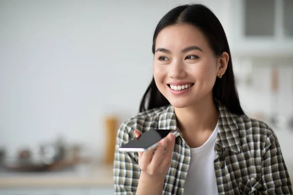 Closeup of smiling asian woman recording voice message while eating — Stock Photo, Image