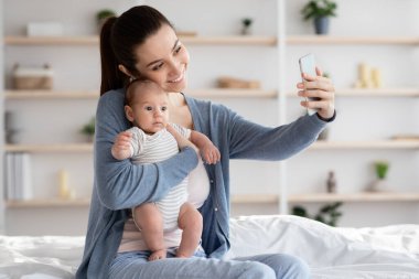Güzel genç anne yeni doğmuş bebeğiyle Selfie çekiyor.