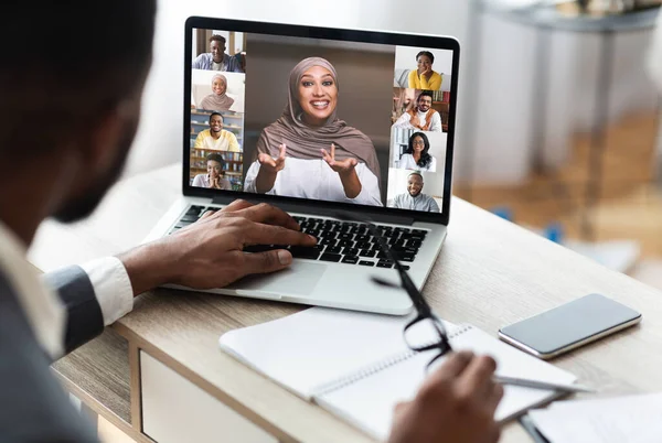 Zadní pohled na černošského podnikatele komunikujícího s kolegy prostřednictvím videokonference — Stock fotografie
