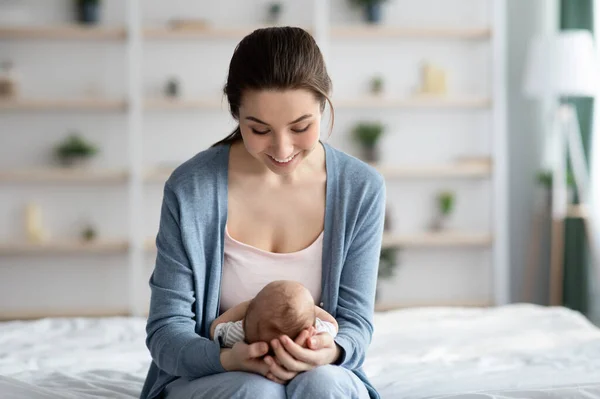 A fiatal boldog nő otthon tölti az idejét az újszülött kisbabájával — Stock Fotó