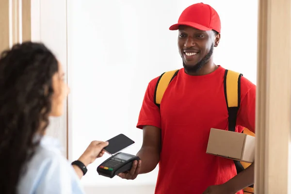 Schwarzer Mann hält Kassen-Kundin, die mit Smartphone bezahlt — Stockfoto