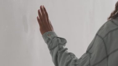 Yeni ev sahibi. Yeni dairesinde beyaz duvarı okşayan mutlu Afro-Amerikan bayan tasarım yenilemesinin keyfini çıkarıyor.