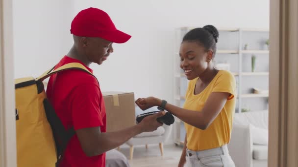 Akıllı kablosuz ödeme. Afro-Amerikalı bir kadın siparişi akıllı saatle, kurye postasıyla ve bağış kutusuyla ödüyor. — Stok video