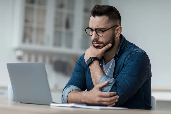 Pensativo empresario pensar en el proyecto en línea, mirar el ordenador portátil en el lugar de trabajo, profesional considerar la solución — Foto de Stock