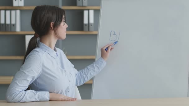 年轻的女英语教师在网上用外语讲解英语，在白板上书写，并与摄像机交谈 — 图库视频影像