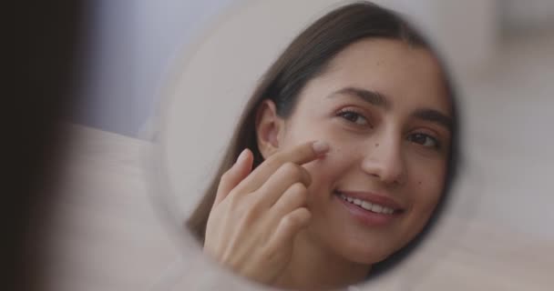 Jovem senhora do Oriente Médio aplicando pontos creme de og em sua bochecha e sorrindo para si mesma, espelho retrato de reflexão — Vídeo de Stock