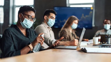 Tıbbi maske takan çok kültürlü işçiler, dezenfektan kullanan siyahi kadınlar.