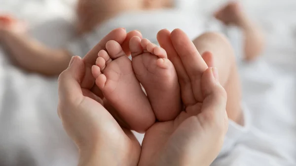 Close-up tiro de minúsculo recém-nascido bebê pés em mães mãos — Fotografia de Stock