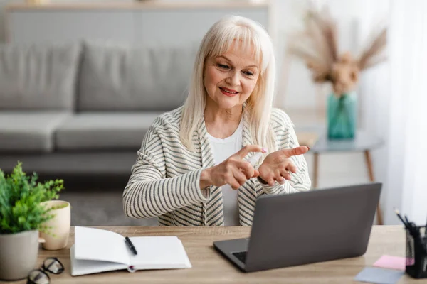 Portret van een oudere vrouw die ontsmettingsmiddel bij de hand heeft — Stockfoto