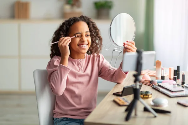 Skönhetsblogg för tonåringar. Glädjande afrikansk amerikansk flicka tillämpa ögonskuggor och spela in kosmetika produktrecension — Stockfoto
