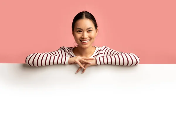 Feliz sorrindo jovem ásia senhora inclinado no branco branco publicidade bordo — Fotografia de Stock