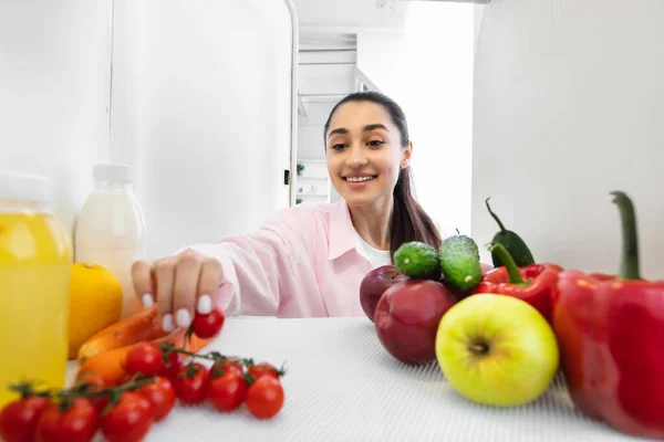 Femme souriante ouvrant le réfrigérateur et prenant de la nourriture — Photo