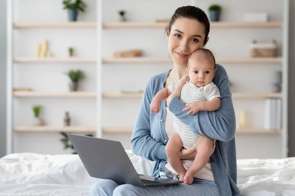 Loisirs des mères. Femme avec bébé nouveau-né sur les mains en utilisant un ordinateur portable à la maison — Photo