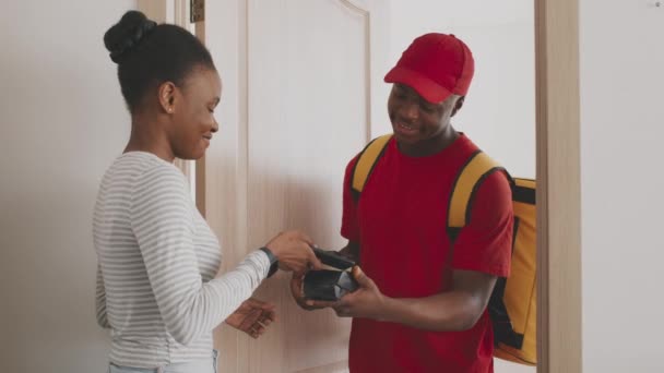 Genç Afro-Amerikalı bayan kuryeden kahve alıyor, siparişi akıllı telefonla ödüyor, ağır çekimde. — Stok video
