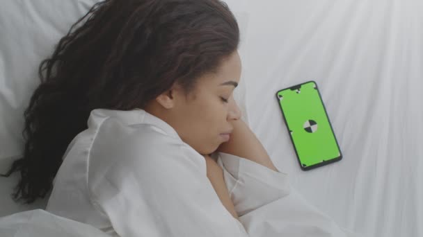 Ruido blanco para dormir bien. Vista superior a la dama afroamericana durmiendo en la cama, teléfono inteligente con pantalla clave de croma verde — Vídeos de Stock