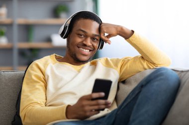 Neşeli siyah adam cep telefonundan film izliyor.