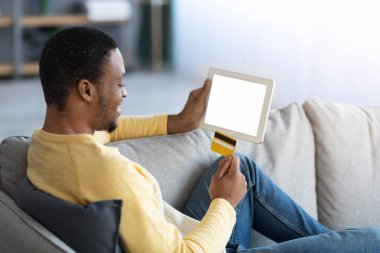 Kredi kartı ve dijital tableti olan Afrikalı Amerikalı bir adam.
