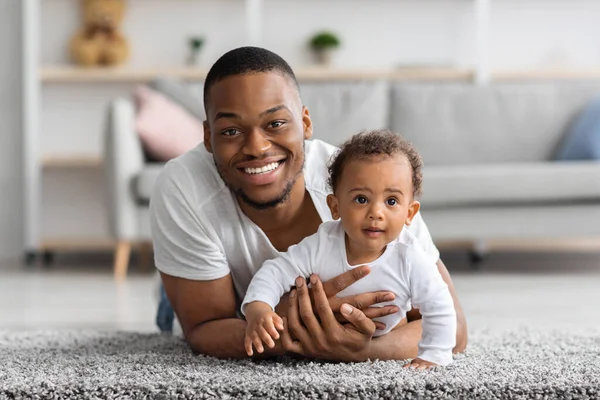 Portret van knappe jonge zwarte vader met schattige pasgeboren baby thuis — Stockfoto