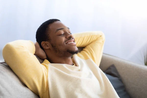 Primer plano del tipo negro reclinado en el sofá con los ojos cerrados — Foto de Stock