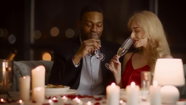 Пара пьющих игристое вино наслаждаясь ужином в ресторане — стоковое видео