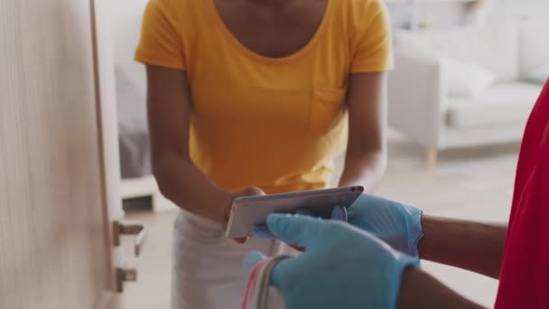 Moda endüstrisi ve kıyafet teslimatı. Tanınmayan bir kadın tabletten sipariş için imza atıyor ve kuryeden çanta alıyor. — Stok video