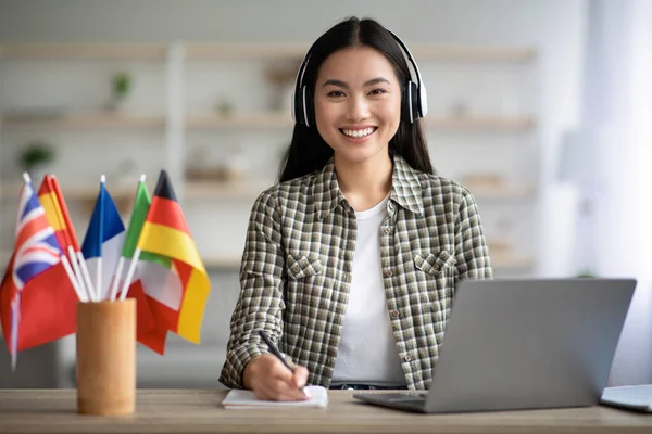 Smiling asian lady using laptop and headset, learning foreign language — Stock Photo, Image