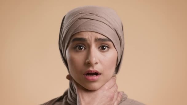 Mano masculina agarre mujer musulmana por la garganta sobre fondo beige — Vídeo de stock