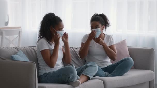 African american mother with her teen daughter putting on protective medical masks before going out, woman helping girl — Stock Video