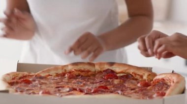 Fast food teslimat servisi. İki tanınmayan Afrikalı Amerikalı genç kız evdeki kutudan taze pizza yiyorlar.