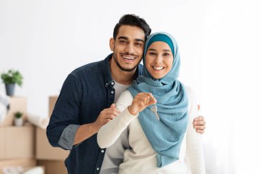 Mutlu Arap ailesi kucaklaşıyor ve dairenin anahtarını gösteriyor.