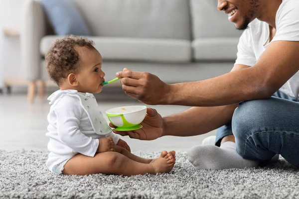 Afro-Amerikaanse vader voeden zijn schattige baby zoon met lepel — Stockfoto