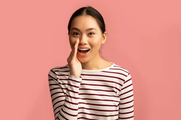 Hermosa mujer asiática sosteniendo la mano cerca de la boca, compartiendo noticias o chismes —  Fotos de Stock
