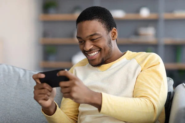 Chico negro feliz jugando en el teléfono móvil — Foto de Stock