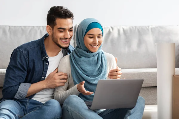 Primo piano della famiglia araba amorevole utilizzando il computer portatile a nuova casa — Foto Stock