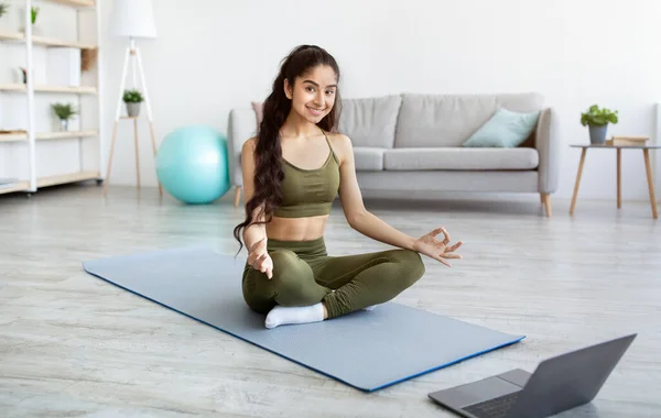 Vreedzame Indiase vrouw met online meditatie of yoga klasse, zittend in lotus poseren voor laptop thuis — Stockfoto