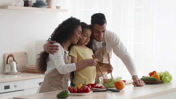 Fröhliche arabische Familie kocht gemeinsam Gemüsesalat in der Küche — Stockfoto