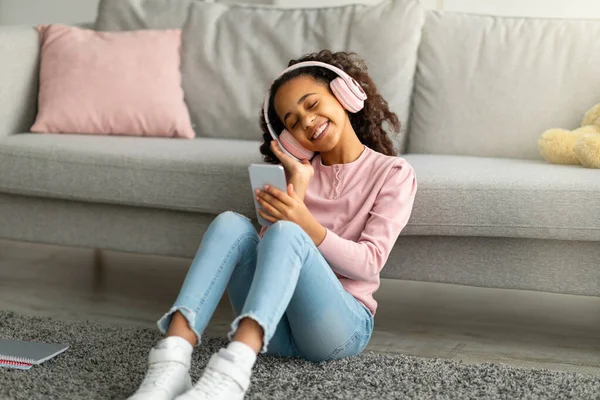 Tempo libero moderno. Felice adolescente afroamericano ragazza godendo canzoni preferite, indossando cuffie wireless — Foto Stock
