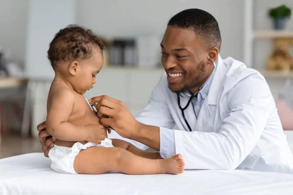 Médico pediatra preto fazendo check-up para bebê recém-nascido bonito em fralda — Fotografia de Stock