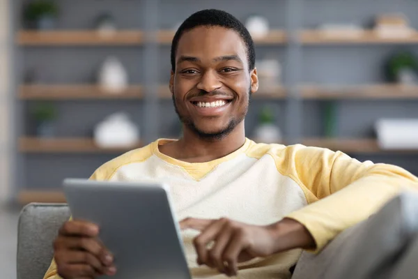 Alegre negro chico descansando con digital tablet en sofá — Foto de Stock