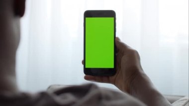 Tanımlanamayan Afro-Amerikan bir adamın elinde yeşil renkli ekranlı modern akıllı telefon tutuşu.