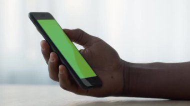 Tanımlanamayan siyah adam elinde yeşil renkli ekranlı akıllı telefon tutuyor ve video seyrediyor. Model için boş bir alan.