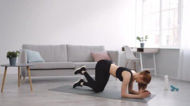 Fitness Kadını Kalça Egzersizi Yapıyor. Dört ayak üstünde ayakta, içeride bacağını kaldırıyor.