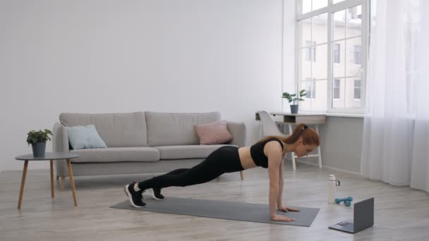 Kvinnan gör Axelberöring Plank Motion på laptop hemma — Stockvideo
